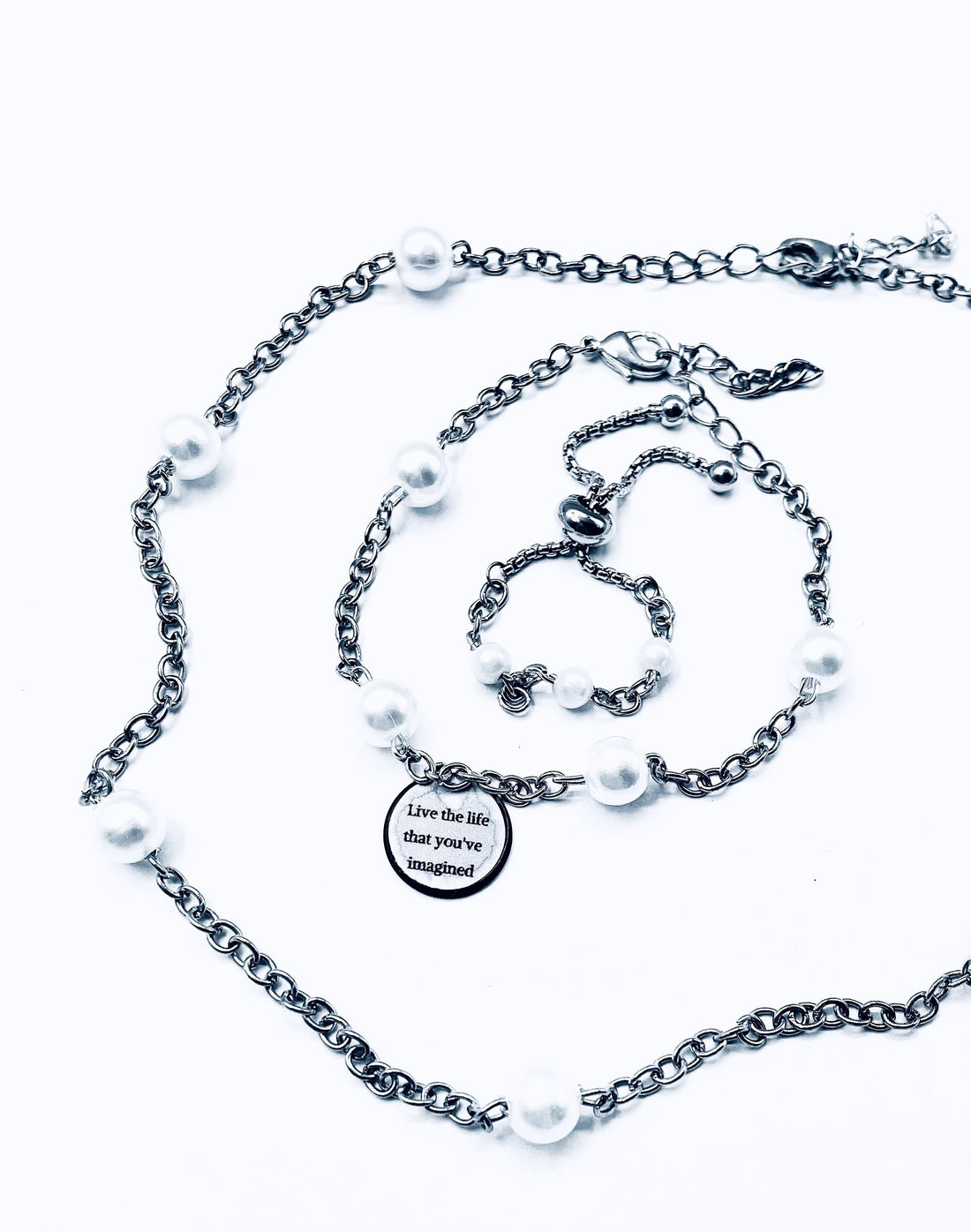 A necklace, bracelet, and earrings set, made with silver chain and imitation pearls, and with an inspiring reminder tag attached that says, 'Live the life that you've imagined'.