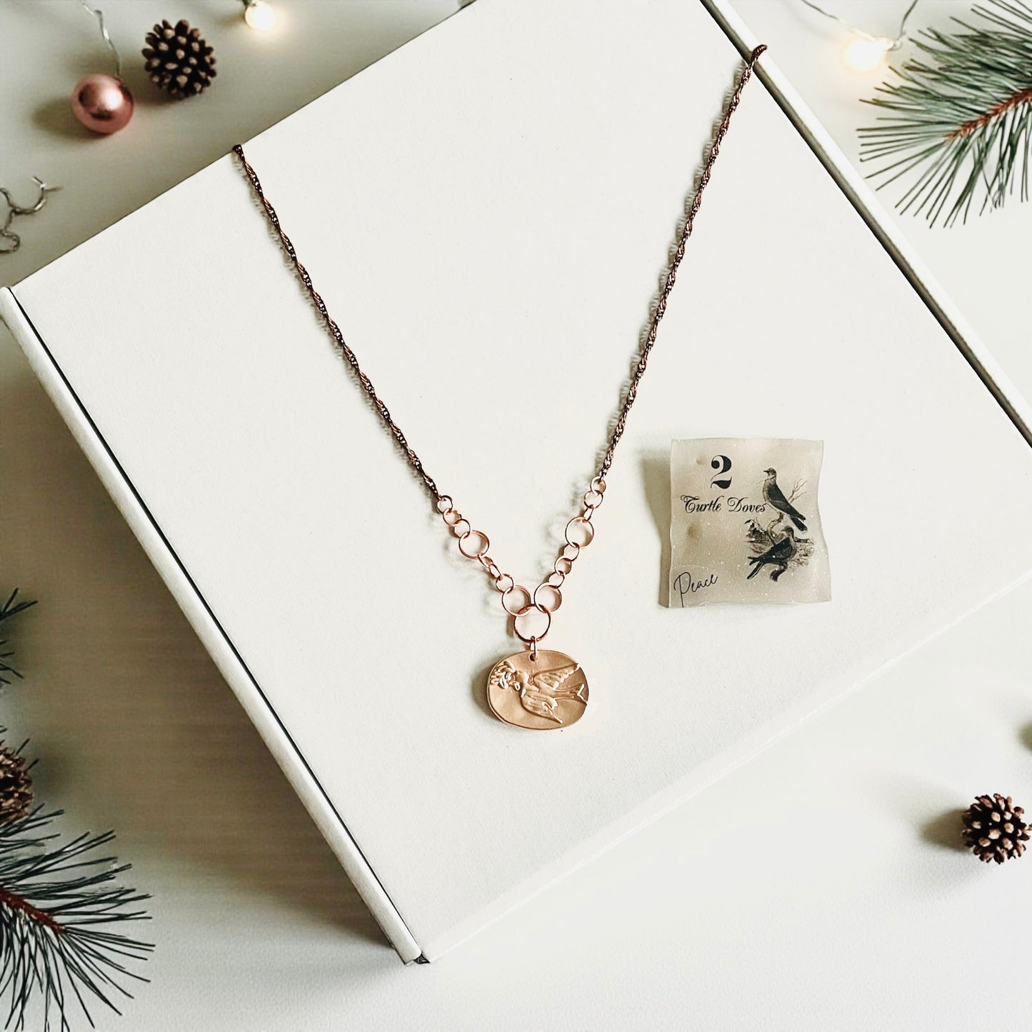 Necklace with a pendant on a white box with Christmas decorations around